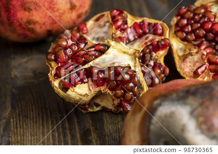 Rotten spoiled red ripe pomegranate on the board Rotten spoiled red ripe pomegranate on the board 98730365