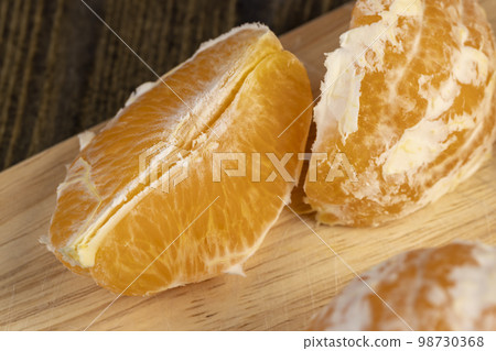 Peeled orange divided into slices on a board Peeled orange divided into slices on a board 98730368