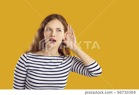 Curious young woman listening to gossip or eavesdropping on someone's conversation Curious young woman listening to gossip or eavesdropping on someone's conversation 98730369