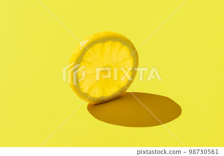 Lemon slice minimalist on a yellow background Lemon slice minimalist on a yellow background 98730561