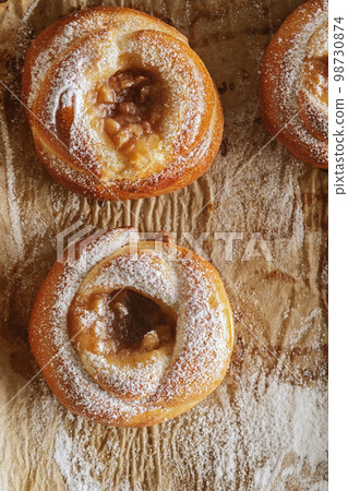 Freshly baked pastries with jam on baking paper decorated with sugar powder Freshly baked pastries with jam on baking paper decorated with sugar powder 98730874