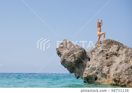 8-year-old happy boy in a victory pose stands on a rock 98731136