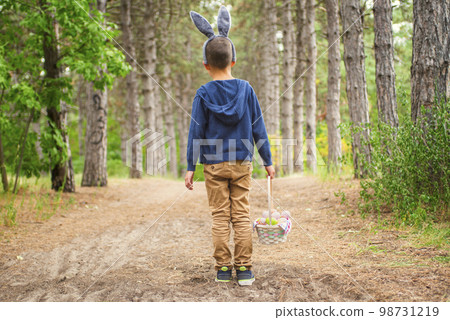 A child looking for Easter eggs in the forest. Little boy hunting for Easter egg A child looking for Easter eggs in the forest. Little boy hunting for Easter egg 98731219