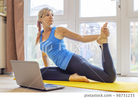 Beautiful woman in sportswear doing sport exercises on yoga mat at home 98731235