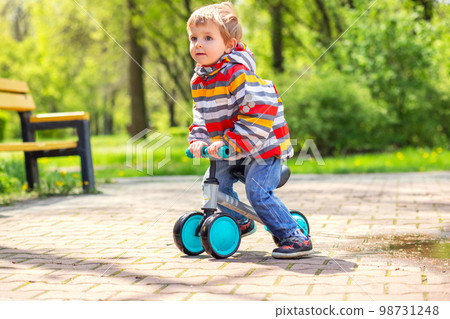 Active blond boy riding balance bike or run bike outdoor park Active blond boy riding balance bike or run bike outdoor park 98731248