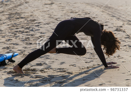 a woman, most likely young, is warming up in front of a surfing 98731337