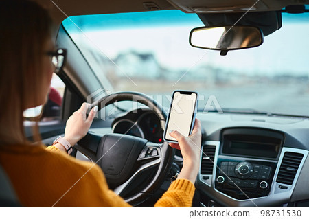 woman driver using mobile phone screen blank mockup on the road while driving a car 98731530