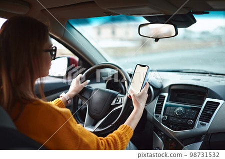 woman driver using mobile phone screen blank mockup on the road while driving a car woman driver using mobile phone screen blank mockup on the road while driving a car 98731532
