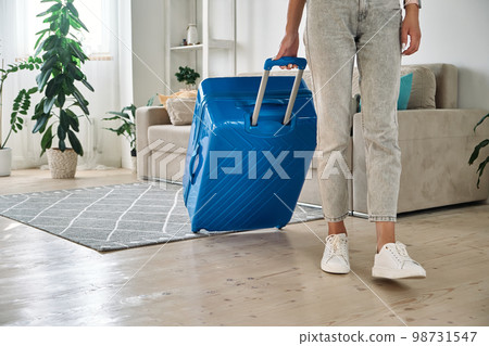 Unrecognizable woman leaving home with a suitcase going on a trip or vacation 98731547