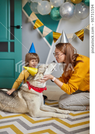Dog pet birthday, family mother and child hug and kiss their dog congratulating happy birthday Dog pet birthday, family mother and child hug and kiss their dog congratulating happy birthday 98731594