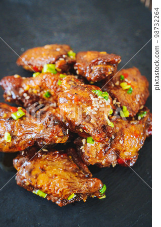 fried chicken with garlic and sesame in caramel on a black tray. fried chicken with garlic and sesame in caramel on a black tray. 98732264