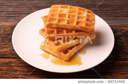 Delicious Belgian waffles with honey served on white plate and wooden background, rustic concept. Delicious Belgian waffles with honey served on white plate and wooden background, rustic concept. 98732408