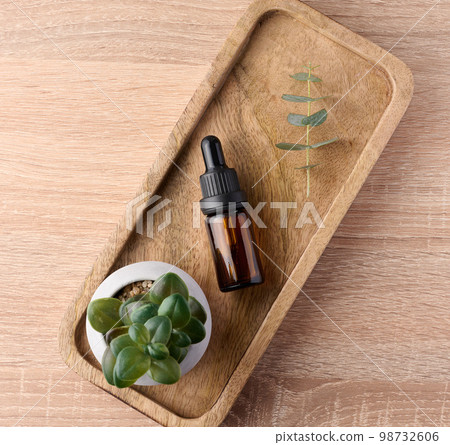 Brown glass bottle with a pipette on a wooden stand 98732606