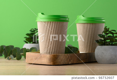 Paper brown cups with a plastic green lid for coffee and tea on a green background 98732607