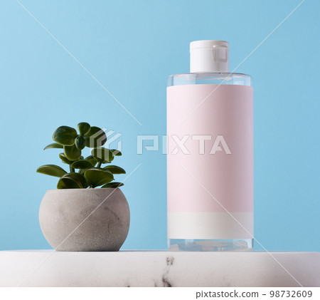 Blank bottle for cosmetics with pink paper label on a blue background. Bottle for tonic, gel Blank bottle for cosmetics with pink paper label on a blue background. Bottle for tonic, gel 98732609
