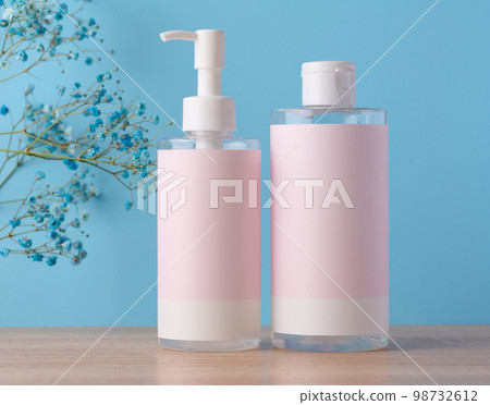 Two bottles for cosmetics with a pink paper label on a blue background. Bottle for tonic, gel Two bottles for cosmetics with a pink paper label on a blue background. Bottle for tonic, gel 98732612