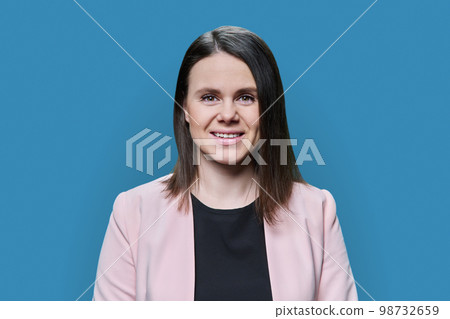 Smiling young woman looking at camera on blue background 98732659