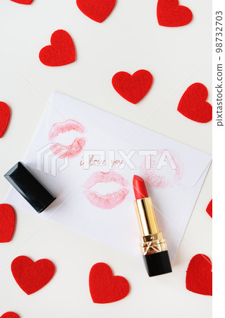 The inscription I love you on a white envelope with a print of lips with red lipstick on a background of small red hearts. The concept of St. Valentine's Day. 98732703