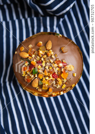 An Easter cake decorated with candied fruits stands on a striped blue apron. Easter religious holiday concept. 98732705