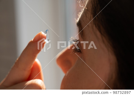 Close-up portrait caucasian woman putting on a contact lens. Close-up portrait caucasian woman putting on a contact lens. 98732897