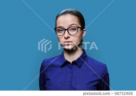 Headshot portrait of young female student looking at camera on blue background 98732988