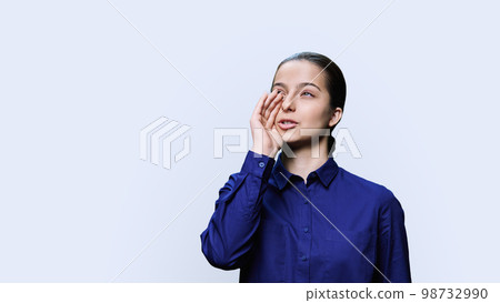 Teenage girl talking to the side, copy space, white studio background 98732990