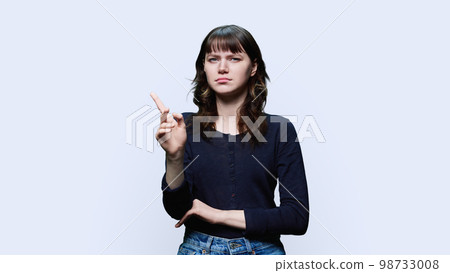 Dissatisfied young female looking at camera on white background Dissatisfied young female looking at camera on white background 98733008