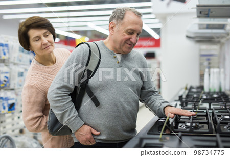 Middle aged wife and husband picking new gas stove in store 98734775