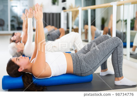 Young woman practicing pilates with roller in gym room Young woman practicing pilates with roller in gym room 98734776