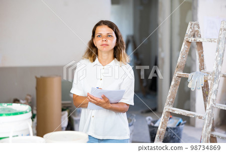 Female architect matching check list during repair works 98734869