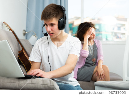 Teenager boy addicted with laptop 98735003