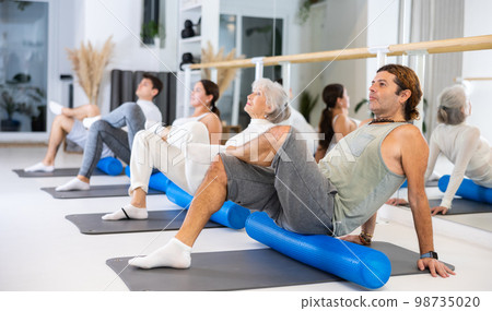 Group of different people doing exercises with roller 98735020