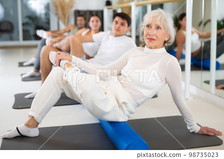 Women and men doing stretching workout during group training in yoga class Women and men doing stretching workout during group training in yoga class 98735023