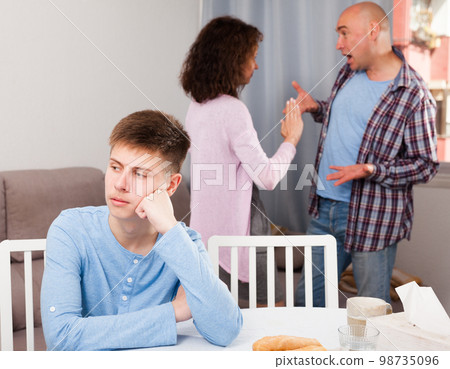 Unhappy teen boy with quarreling parents Unhappy teen boy with quarreling parents 98735096