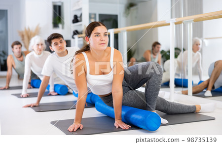 Group of different people doing exercises with roller 98735139