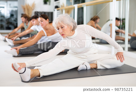 Аctive senior woman performs exercises on a pilates mat in the hall of a modern fitness studio. Аctive senior woman performs exercises on a pilates mat in the hall of a modern fitness studio. 98735221