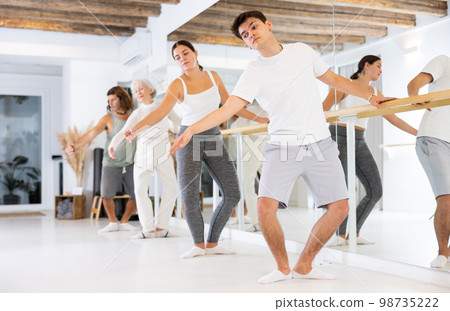 Group of different people doing ballet at barre 98735222