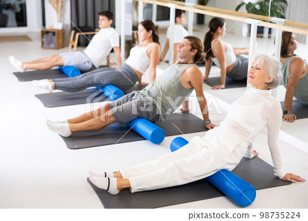 Group of different people doing exercises with roller Group of different people doing exercises with roller 98735224