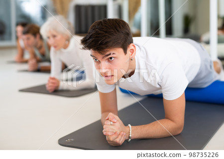 Young man practicing pilates with blue roller in gym room Young man practicing pilates with blue roller in gym room 98735226