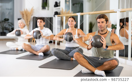Men and women doing pilates exercises with fitness ball at gym Men and women doing pilates exercises with fitness ball at gym 98735227
