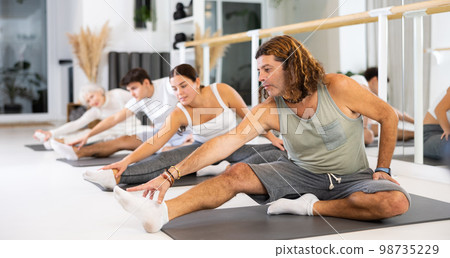 Portrait of flexible women and men practice yoga in modern studio. Portrait of flexible women and men practice yoga in modern studio. 98735229