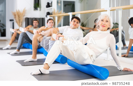 Group of different people doing exercises with roller 98735248