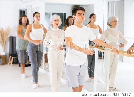 Group of different people doing ballet at barre 98735337