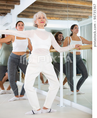 Elderly woman doing ballet at barre Elderly woman doing ballet at barre 98735367