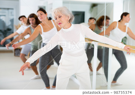 Elderly woman doing choreography at ballet barre 98735374