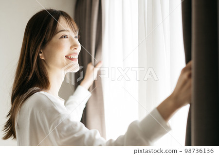 Woman opening the curtain, wake-up image 98736136