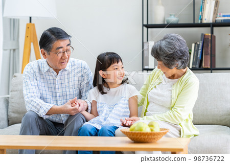 Granddaughter and grandparents in the living room 98736722