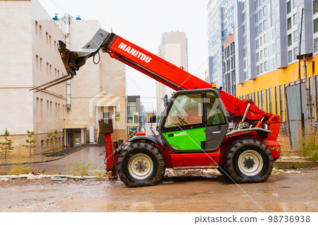 telescopic loader handler. Red Manitou telehandler at construction site after rain. Side view, lifestyle photo. 98736938
