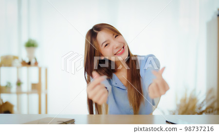 Happy teen asian girl blogger smiling and heart hand talking to webcam recording vlog 98737216