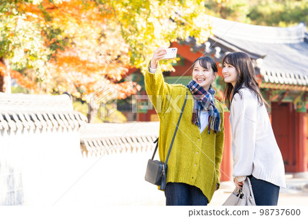 Young woman taking a commemorative photo with a smartphone Young woman taking a commemorative photo with a smartphone 98737600